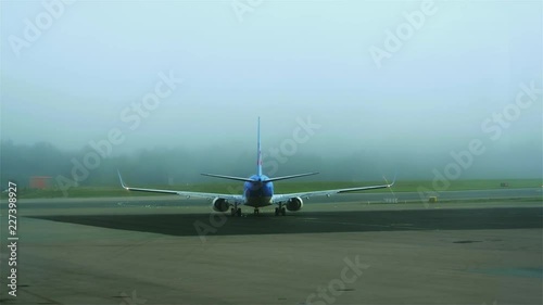 A blue and white airplane slowly starts to move towards the runway on a foggy day at Stockholm Arlanda. No camera movement. Filmed in UHD 4K. photo