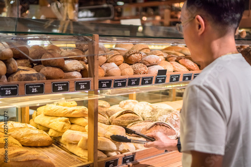 Man shopping in supermarket ,choosing bread in the store