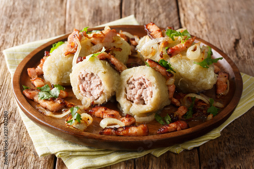 Lithuanian food: Cepelinai boiled potato dumplings with minced meat served with bacon, parsley and fried onions close-up. horizontal