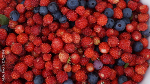 wild strawberries and blueberries are scattered close-up