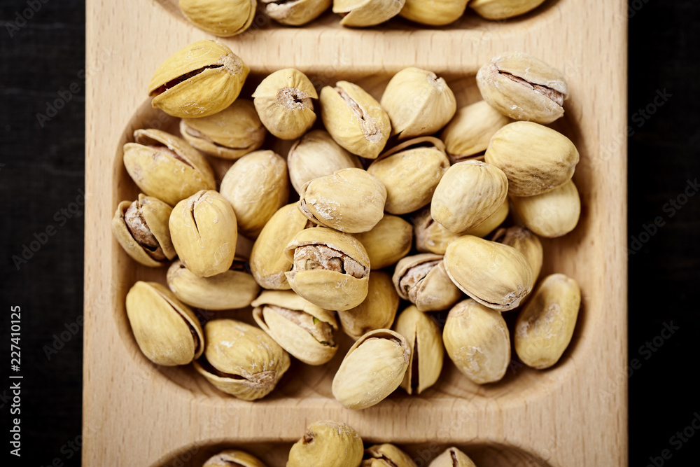 delicious pistachios on a wooden plate on an old black table in a pub delicious pistachios on a wooden plate on an old black table in a pub