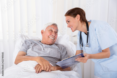 Nurse With Clipboard Visiting Senior Patient