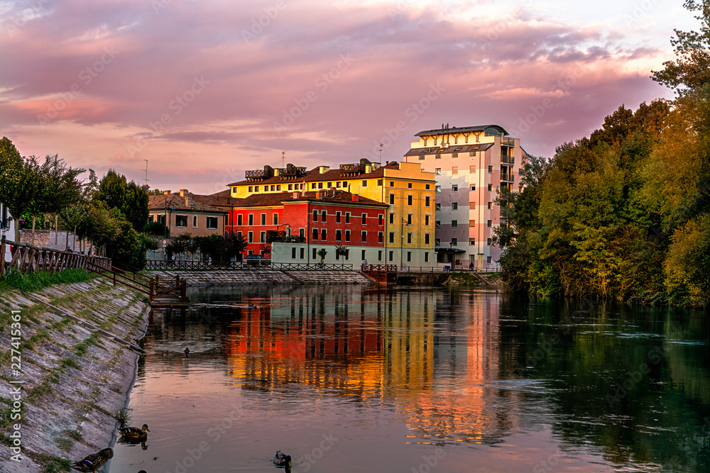 Treviso, the restera esplanade at sunset in autumn. House reflections on the river Sile.