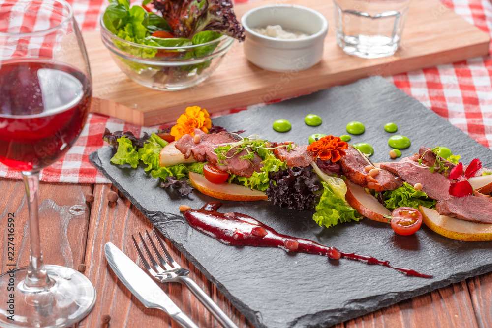 Tasty sliced roast duck breast with fresh vegetable salad closeup on a plate.