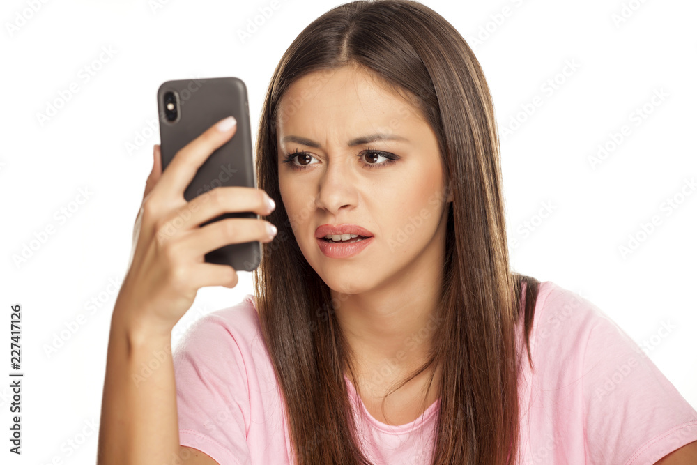 dissatisfied young woman look in her smartphone on white background dissatisfied young woman look in her smartphone on white background