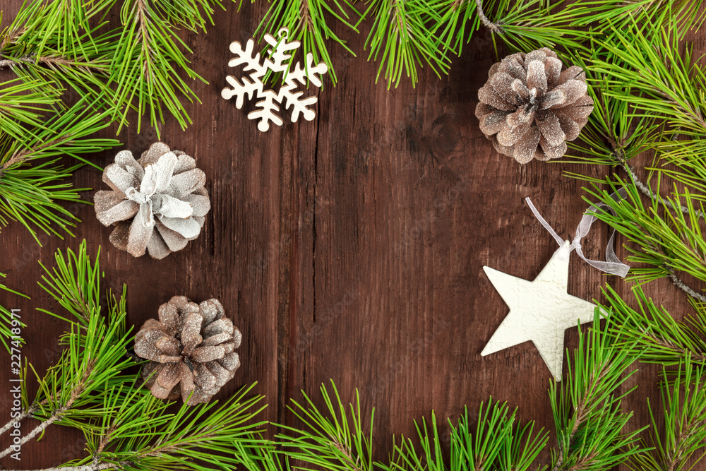 Fototapeta premium Christmas background with fir tree branches, cones, snow and xmas decorations on a dark wooden texture with a place for text