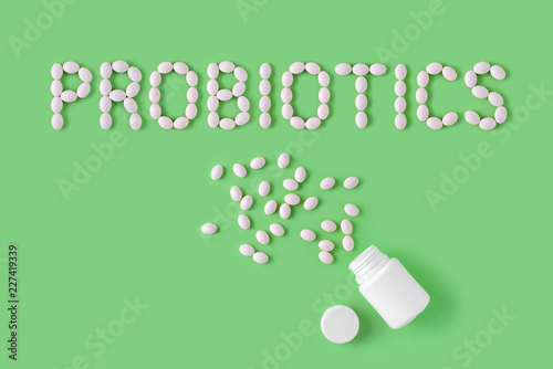 Probiotics word made of pills on green background. Flat lay, top view, free copy space. photo