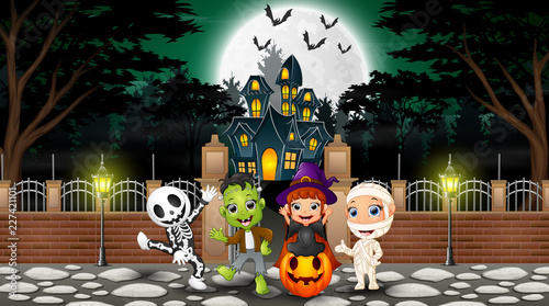 Happy kids wearing halloween costume outdoors with the haunted house background