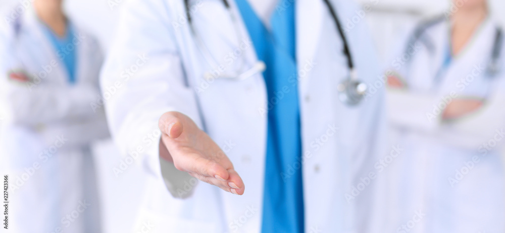Group of medicine doctors offering helping hand for shaking hand or saving life closeup. Partnership and trust concept in health care or medical cure Group of medicine doctors offering helping hand for shaking hand or saving life closeup. Partnership and trust concept in health care or medical cure