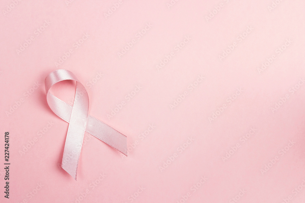 Pink ribbon on pink background withcopy space. Breast cancer awareness symbol. Pink ribbon on pink background withcopy space. Breast cancer awareness symbol.