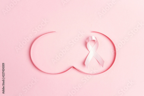 Pink ribbon with breast shape symbol on pink background.  Breast cancer awareness symbol. O