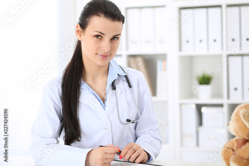 Young brunette female doctor at working place in hospital. Health care, insurance and help concept