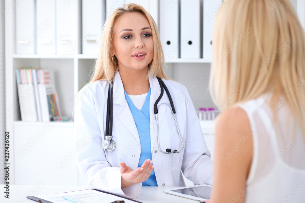Doctor and patient discussing something while sitting at the table at hospital. Medicine and health care concept Doctor and patient discussing something while sitting at the table at hospital. Medicine and health care concept