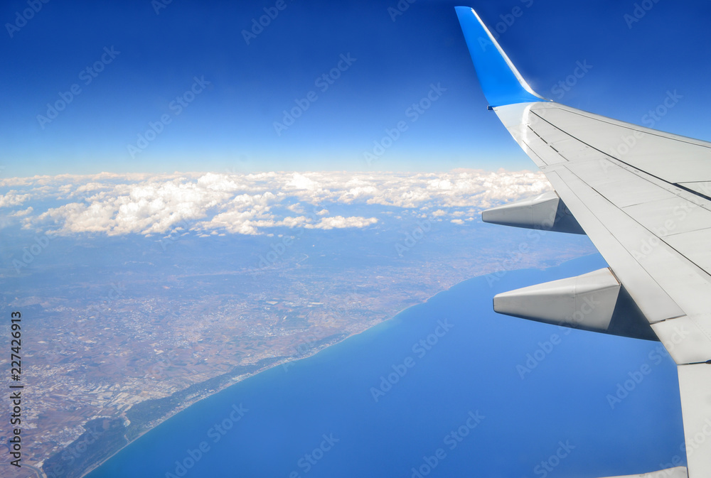 Beautiful view of earth and sea under the wing of plane. Costal city view from above. Travel concept. Freedom concept.