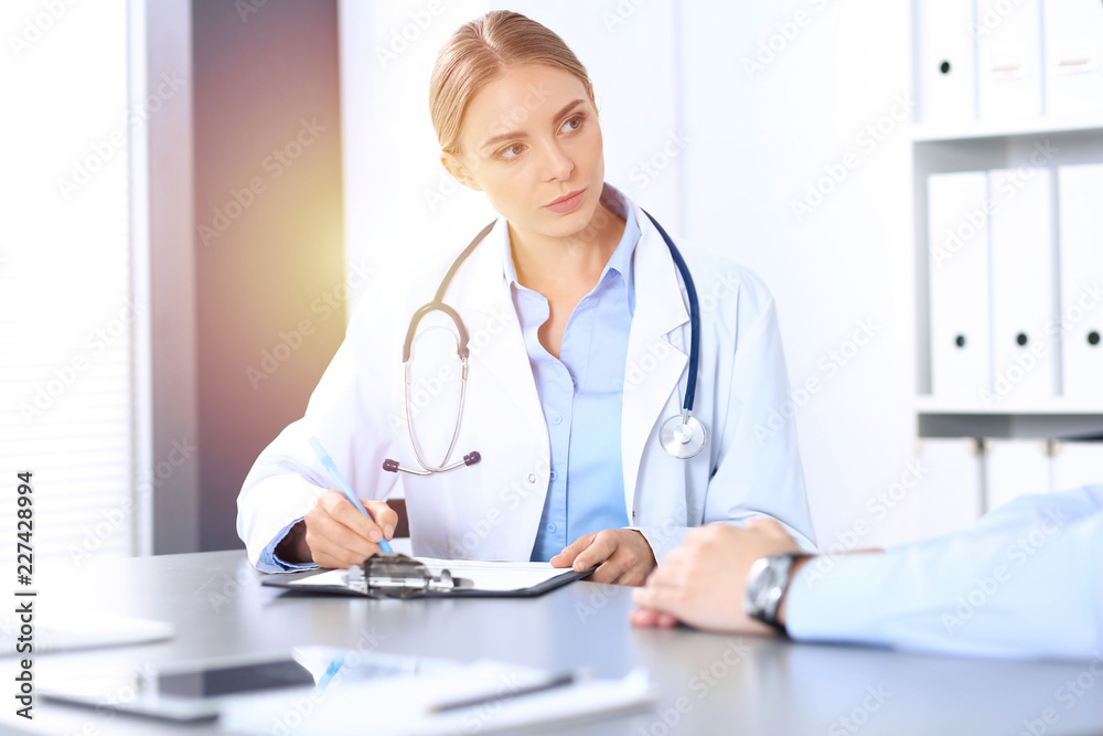 Doctor and patient in hospital. Beautiful blonde physician consulting business man about his health. Medicine concept Doctor and patient in hospital. Beautiful blonde physician consulting business man about his health. Medicine concept