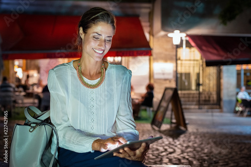 Mature woman using digital tablet at night