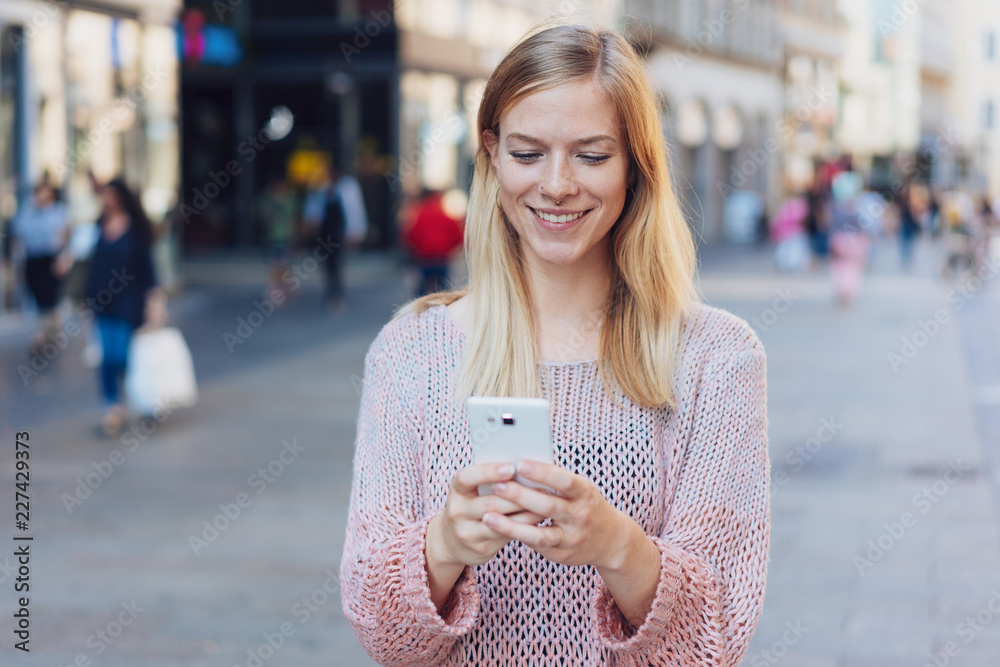 Smiling young woman checking her mobile phone Smiling young woman checking her mobile phone