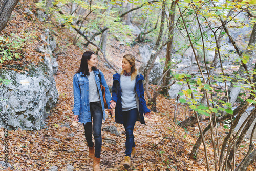 Two young girls friends walking in the autumn forest. Walk in the woods. Girlfriends hiking in the fall. © NesolenayaAleksandra