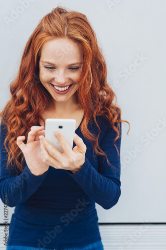 Young smiling red-haired woman using mobile phone photo