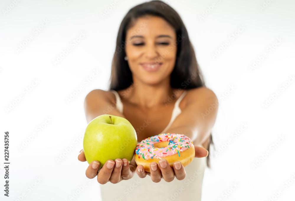 Attractive young woman on a diet deciding between an apple and a doughnut Attractive young woman on a diet deciding between an apple and a doughnut