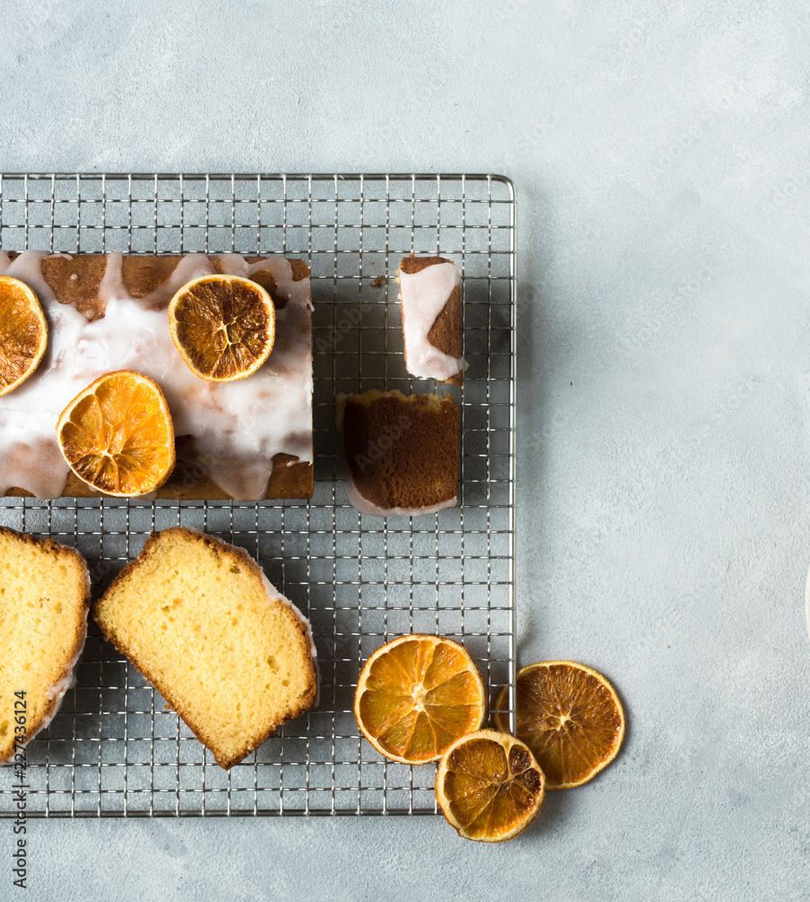 Fototapeta premium Orangenkuchen in Stücke geschnitten und appetitlich drapiert auf grauem hellen Untergrund von oben ohne Menschen bei Tageslicht fotografiert