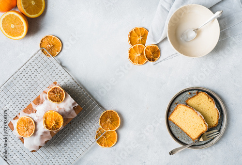 Orangenkuchen in Stücke geschnitten und appetitlich drapiert auf grauem hellen Untergrund von oben ohne Menschen bei Tageslicht fotografiert