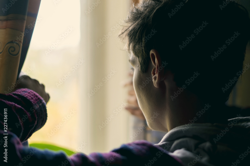 young sad teenager looking through the window f young sad teenager looking through the window f