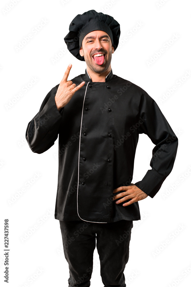 Chef man In black uniform showing tongue at the camera having funny look and taking out the horns on isolated white background Chef man In black uniform showing tongue at the camera having funny look and taking out the horns on isolated white background