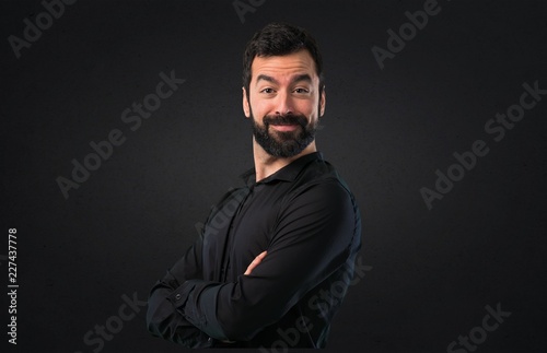 Handsome man with beard with his arms crossed on black background