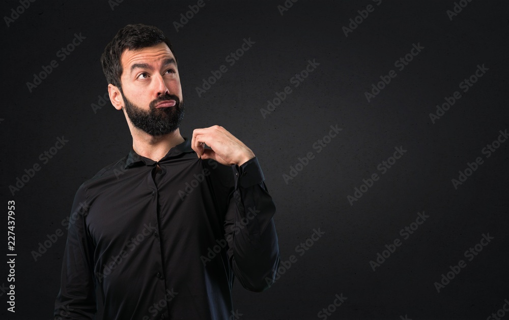 Handsome man with beard proud of himself on black background