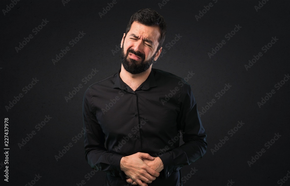 Handsome man with beard with stomachache on black background