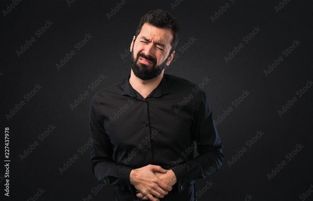 Obraz premium Handsome man with beard with stomachache on black background