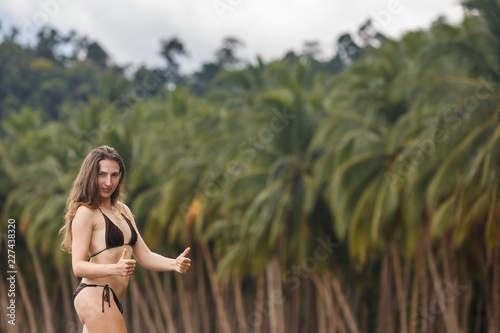 Summer Philippine vacation travel. Happy woman doing thumbs up approving gesture at exotic tropical beach with palm trees background. Palawan, Philippine.