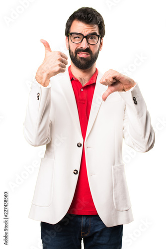 Brunette man with glasses making good-bad sign on white background