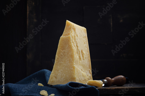 Parmesan cheese on black wooden table with copyspace.