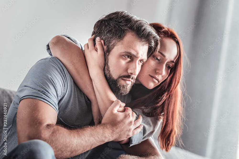 © Viacheslav Yakobchuk - Your support. Sad pleasant young woman sitting together with her boyfriend and hugging him while feeling his support