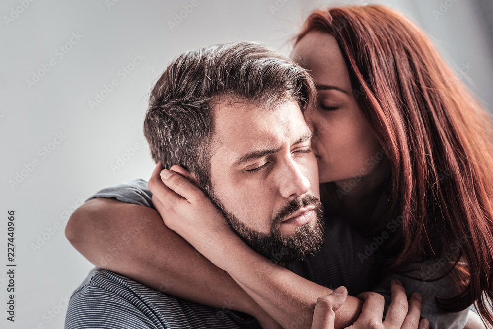 Obraz premium My love. Beautiful nice young woman sitting together with her boyfriend and kissing him while expressing her love