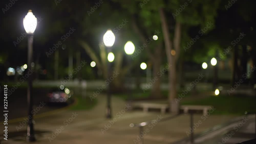 Out of focus video background plate of dark urban park at night