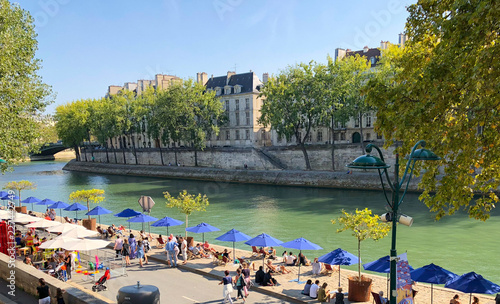 Paris, France, September 1, 2018: Locals gathered under blue umbrellas. Beach on Seine river in the center of Paris,