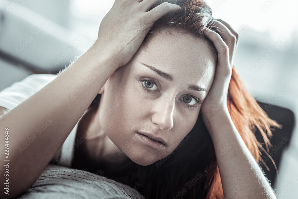 Have a look. Attractive young female lying on couch and raising hands while looking straight at camera Have a look. Attractive young female lying on couch and raising hands while looking straight at camera