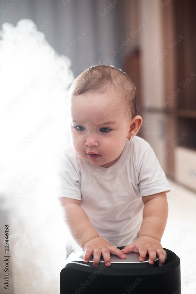 Little baby looks at the humidifier. Moisture in the house concept