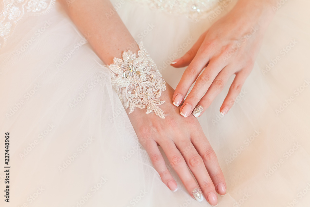 hands of the bride with a beautiful manicure and a bracelet made of lace and rhinestones closeup hands of the bride with a beautiful manicure and a bracelet made of lace and rhinestones closeup