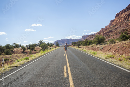 A man walking in the middle of the road in wilderness of Utah