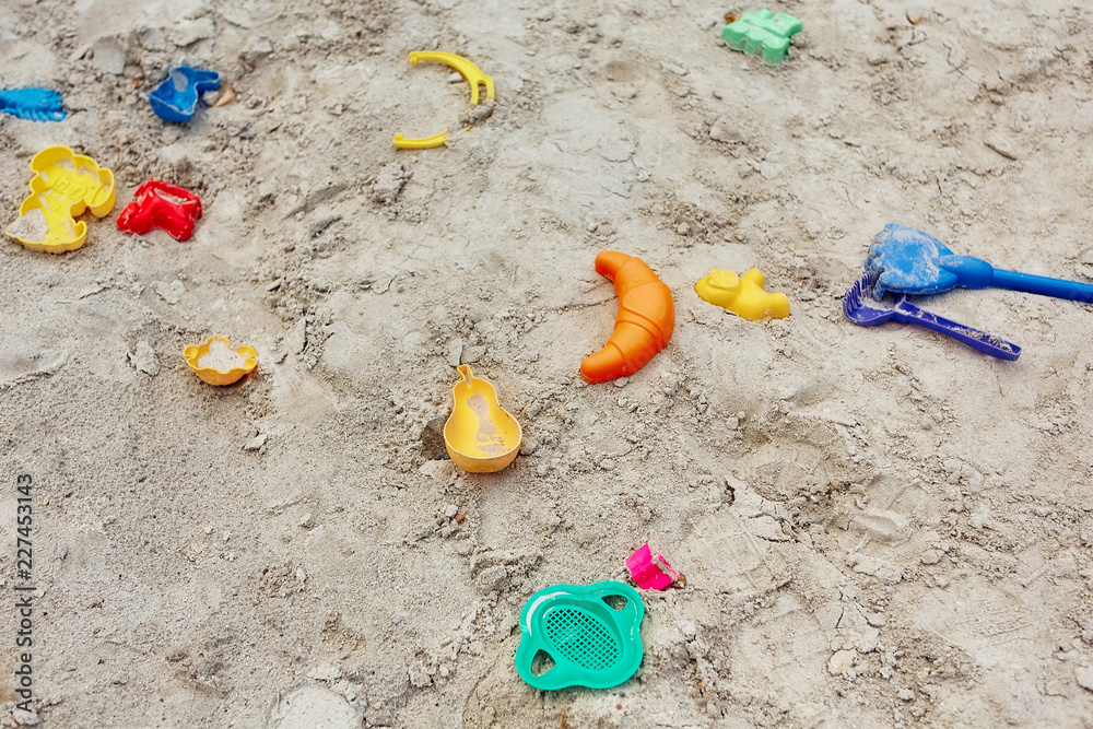 Obraz premium many colored plastic children's toys forgotten in the sandbox