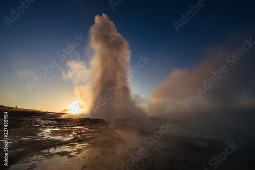 Strokkur geyser eruption in Iceland. Fantastic colors shine through the steam. Beautiful pink clouds in a blue sky