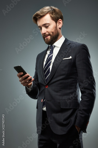 A man in a business suit with a smartphone.