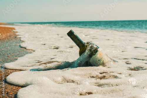 a bottle of wine lying on the sand near the sea
