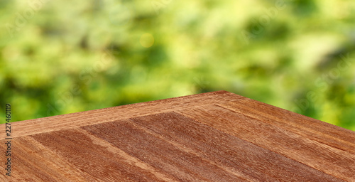 Perspective view of empty wooden table corner on blurry green grass background