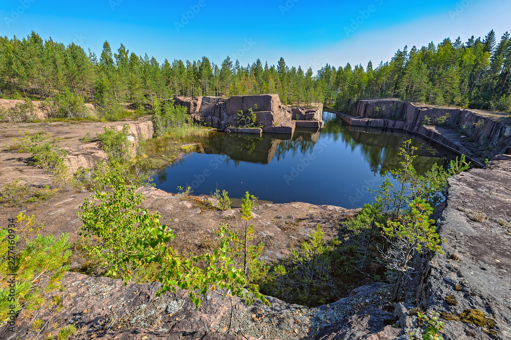 Obraz premium Blue pond formed at the bottom of the abandoned granite quarry.