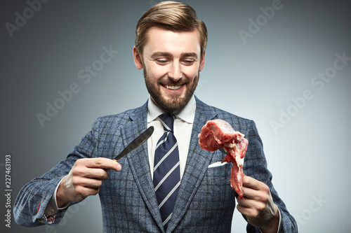 A man in a business suit with a piece of raw meat.